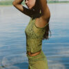 Model showing the lateral side of the "Lace Musgo Stretch" green top from the summer 23/24 Matte collection in a beach in Costa Rica